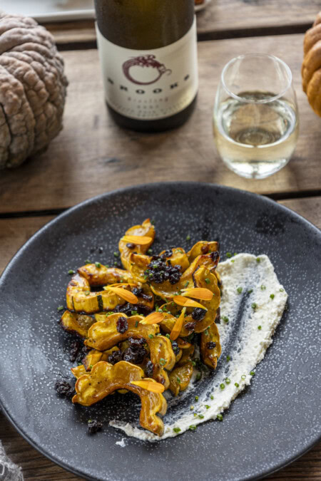 A plate of caramelized delicata squash lays atop a smear of herbed ricotta and paired with a chilled glass of medium-dry Riesling. 