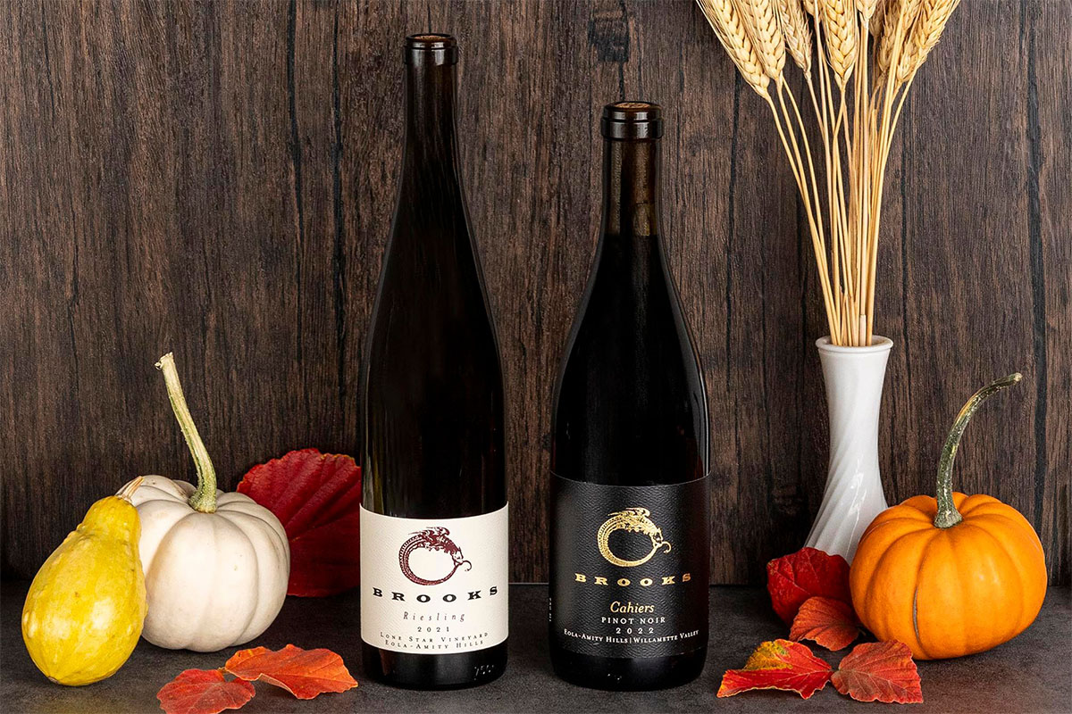 Two wine bottles sit beside a collection of pumpkins on a table, highlighting a festive autumnal setting.