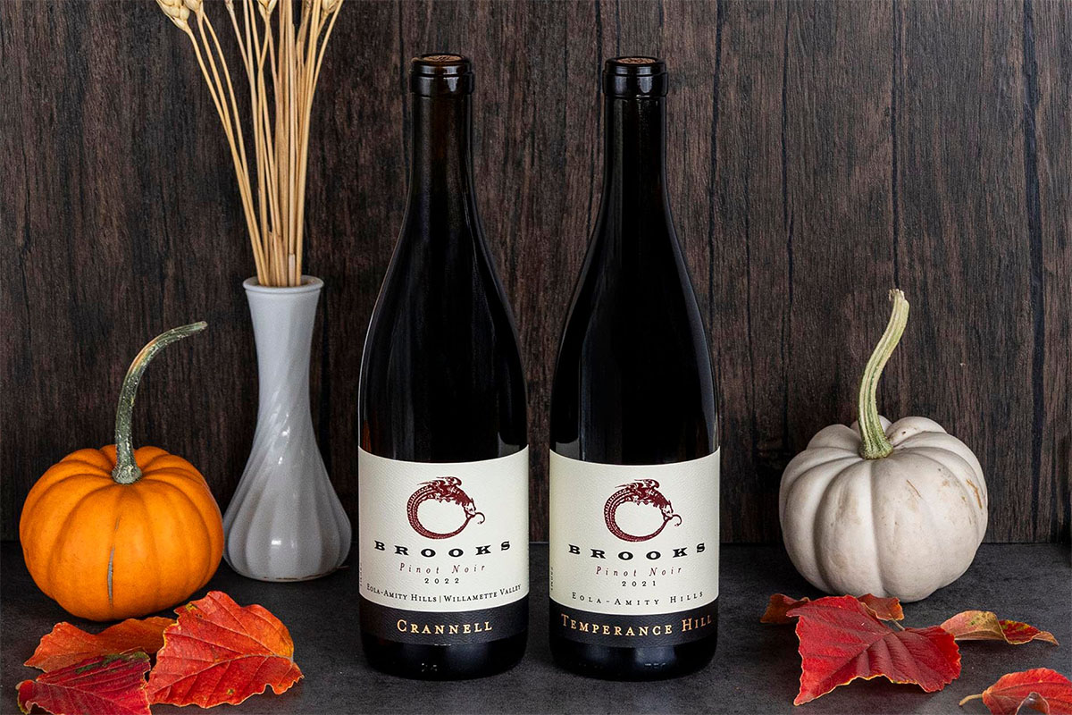 Two wine bottles sit beside a collection of pumpkins on a table, highlighting a festive autumnal setting.