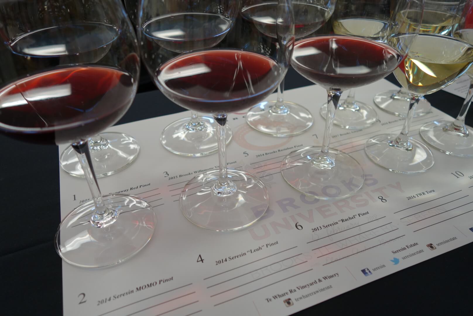 A wine class features a white tasting mat set with four stemmed glasses of white wine and six glasses of red wine.